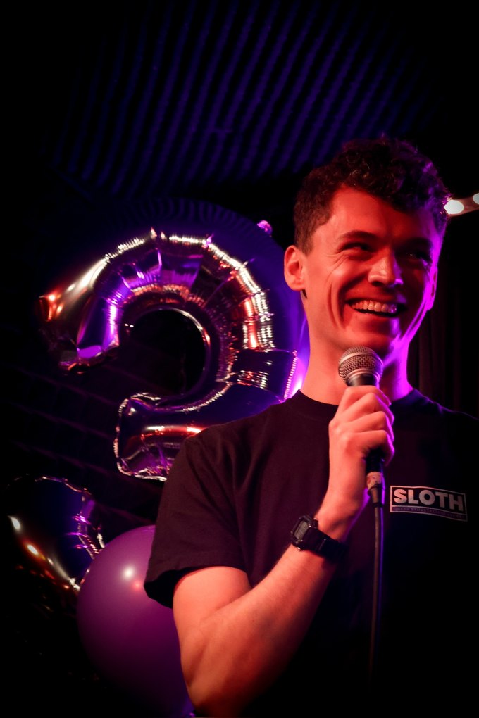 Tyler onstage with a microphone at SLOTH's second-anniversary show